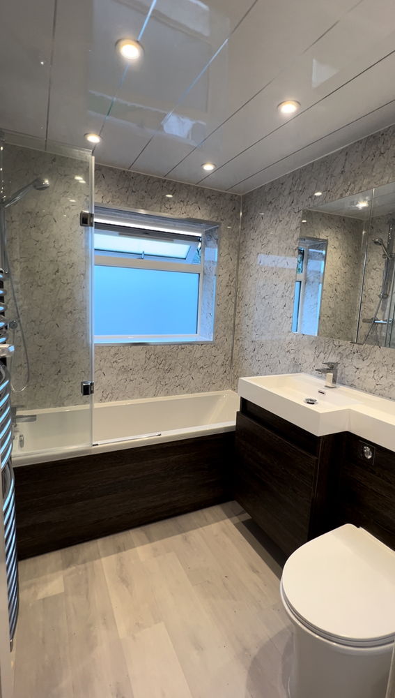Marble-effect bathroom with bath, glass shower screen, dark wood vanity unit and toilet