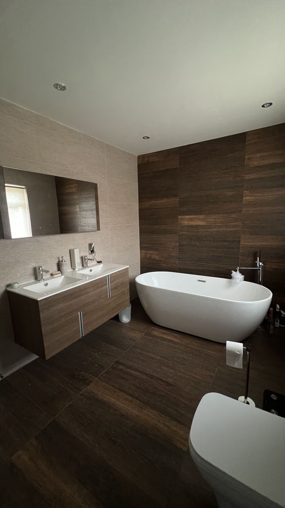 Bathroom with freestanding bath, wood-effect wall and double wood vanity unit